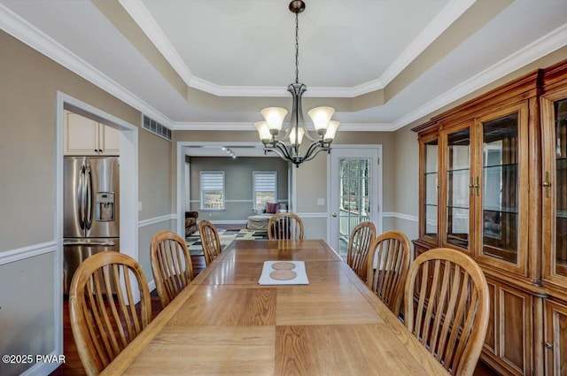 dining area featuring a chandelier, a tray ceiling, visible vents, and crown molding