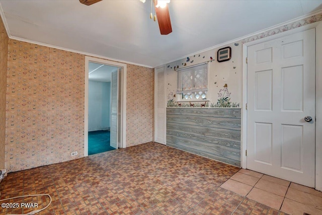 tiled empty room featuring crown molding and ceiling fan