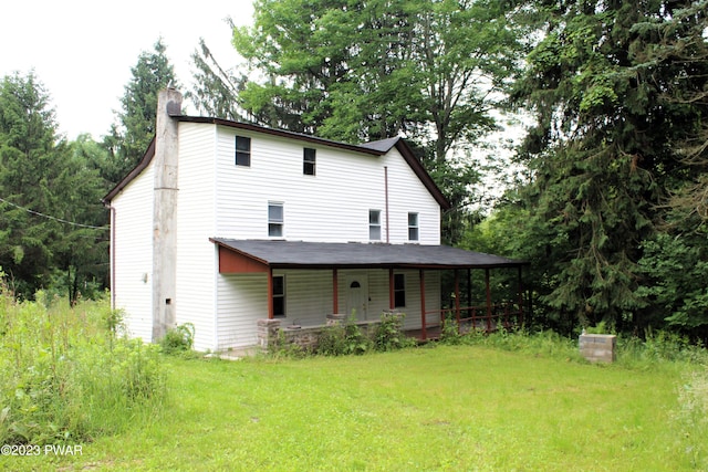 back of property with a lawn and a porch