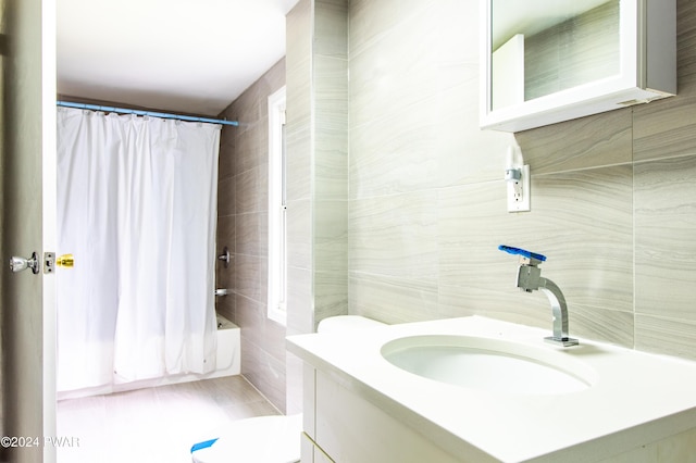 full bathroom with vanity, shower / bathtub combination with curtain, toilet, and tile walls