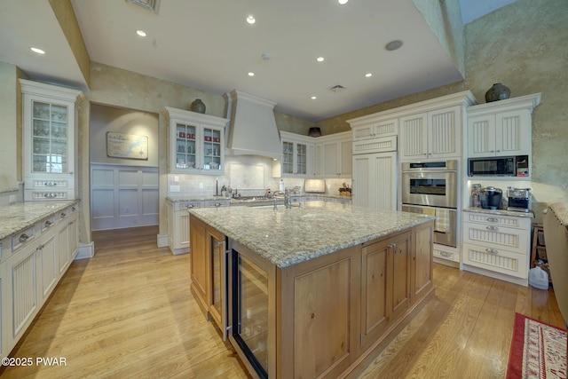 130 Calico Ct, Paupack, PA 18451 - kitchen featuring wine cooler, built in appliances, an island with sink, custom range hood, and light wood-style flooring