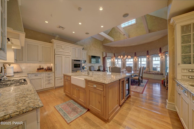 130 Calico Ct, Paupack, PA 18451 - kitchen with light wood finished floors, high vaulted ceiling, stainless steel appliances, a sink, and glass insert cabinets