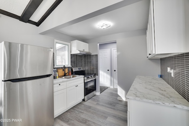 kitchen with appliances with stainless steel finishes, white cabinetry, under cabinet range hood, and light stone counters