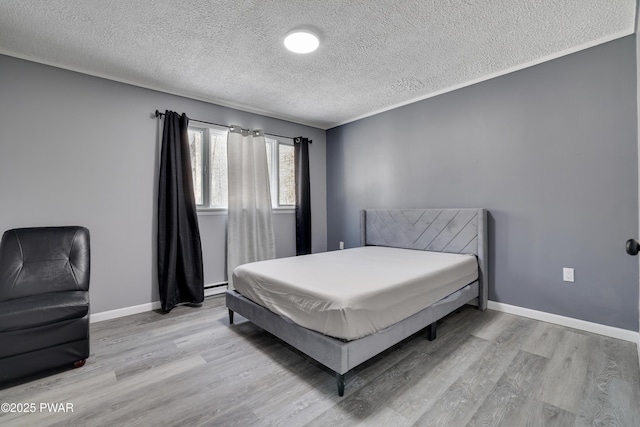 bedroom with a textured ceiling, light wood-type flooring, a baseboard radiator, and baseboards