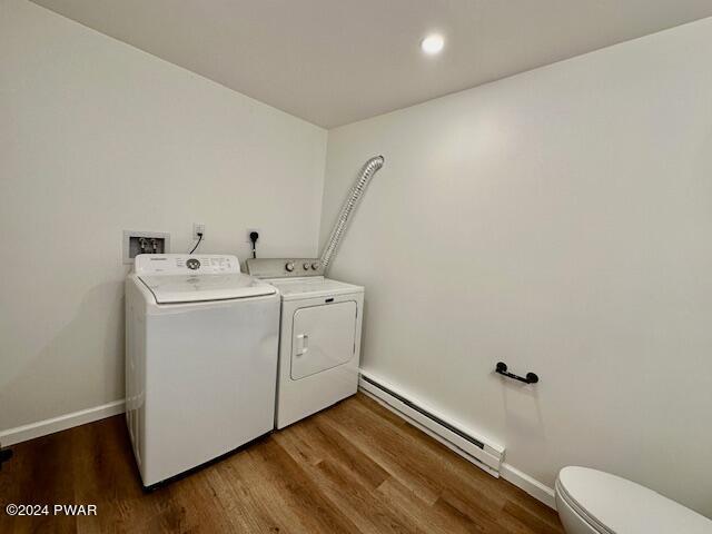 clothes washing area with washer and clothes dryer, wood-type flooring, and a baseboard heating unit