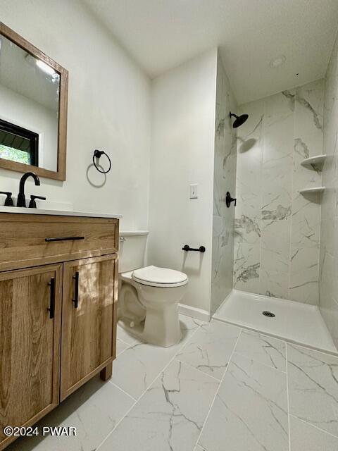 bathroom featuring tiled shower, vanity, and toilet