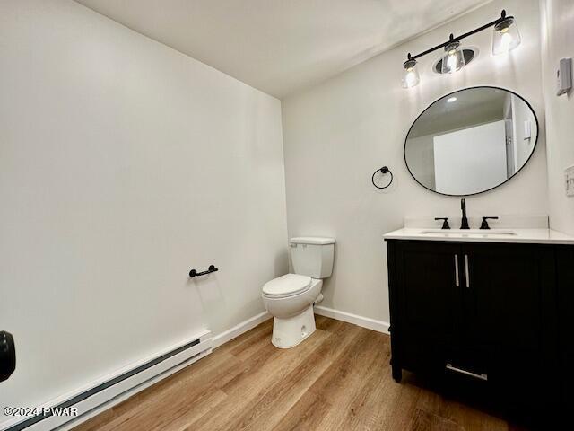 bathroom featuring vanity, toilet, wood-type flooring, and baseboard heating