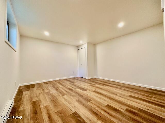 basement featuring a baseboard radiator and light hardwood / wood-style floors