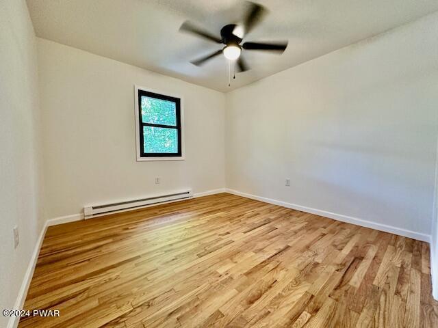 spare room with ceiling fan, light hardwood / wood-style floors, and a baseboard radiator