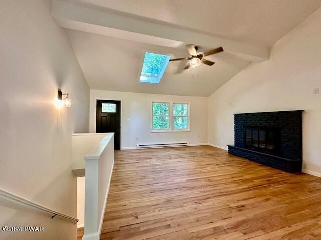 unfurnished living room featuring vaulted ceiling with skylight, ceiling fan, a fireplace, a baseboard radiator, and wood-type flooring