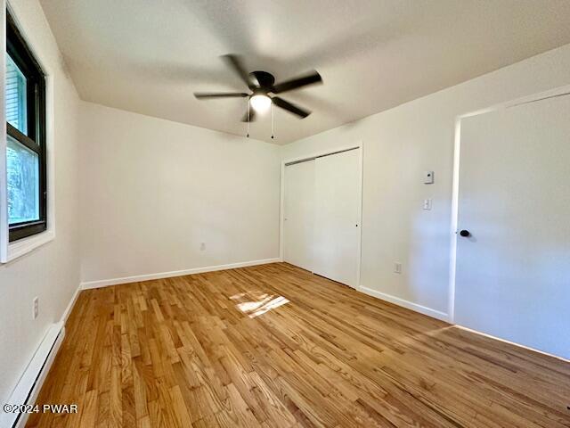 106 Rodeo Ln, Lords Valley, PA 18428 - unfurnished bedroom featuring a baseboard heating unit, light wood finished floors, a closet, and a ceiling fan