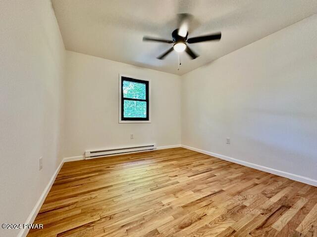 unfurnished room with ceiling fan, light hardwood / wood-style floors, and baseboard heating