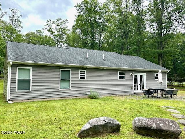 rear view of property with french doors and a lawn