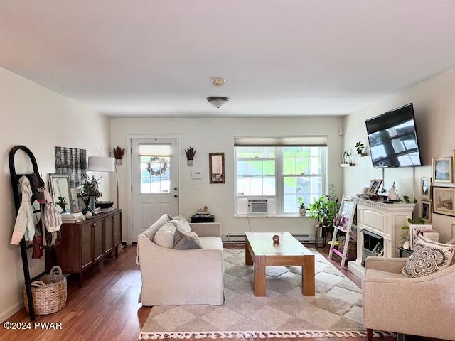 living room featuring hardwood / wood-style floors, cooling unit, and a baseboard heating unit