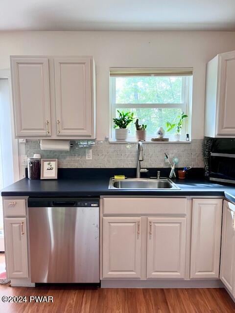 kitchen with sink, light hardwood / wood-style flooring, stainless steel dishwasher, decorative backsplash, and white cabinetry