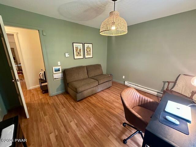 home office featuring wood-type flooring and a baseboard heating unit