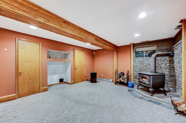 basement with carpet flooring, a baseboard radiator, and a wood stove