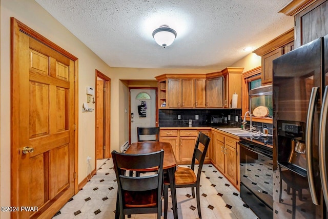 kitchen featuring refrigerator with ice dispenser, decorative backsplash, sink, and a textured ceiling