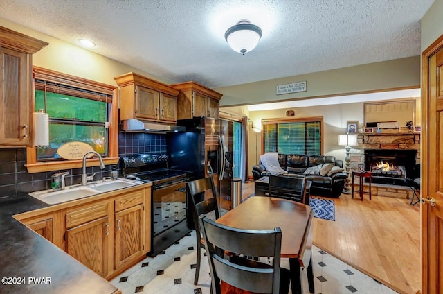 kitchen featuring backsplash, a stone fireplace, sink, electric range, and a textured ceiling