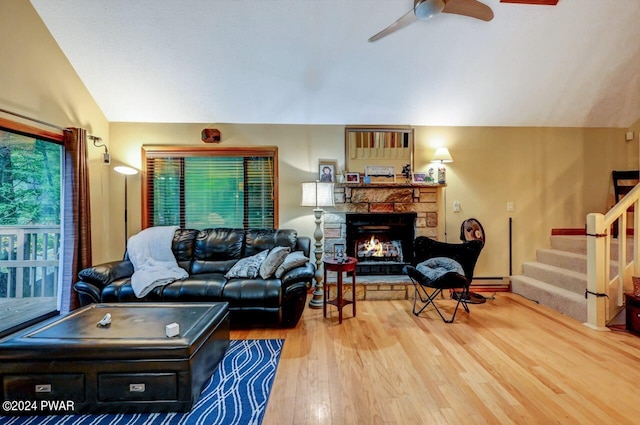 living room with hardwood / wood-style flooring, ceiling fan, a stone fireplace, and lofted ceiling