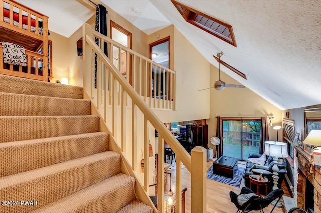 stairway featuring a textured ceiling, ceiling fan, wood-type flooring, and vaulted ceiling