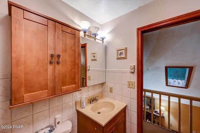 bathroom featuring tile walls, vanity, a textured ceiling, and toilet