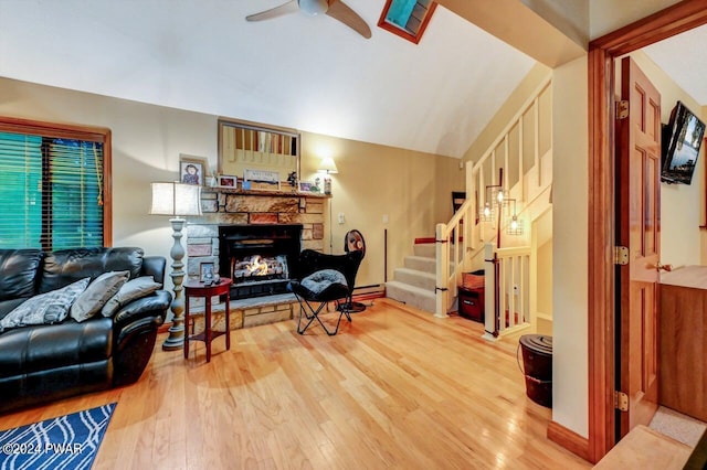 living room featuring ceiling fan, a fireplace, wood-type flooring, and lofted ceiling