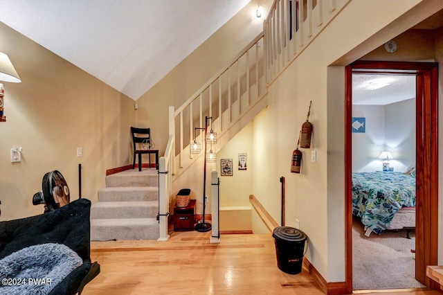 stairs featuring wood-type flooring and vaulted ceiling