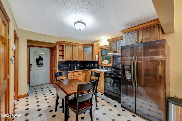 kitchen with sink, black range with electric cooktop, stainless steel refrigerator with ice dispenser, a textured ceiling, and decorative backsplash