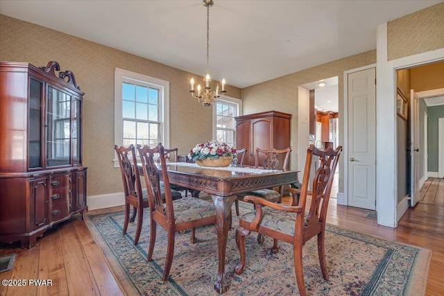 dining room with a chandelier, baseboards, and light wood finished floors