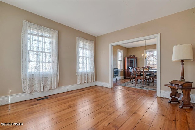 unfurnished room featuring light wood-style floors, visible vents, and baseboards
