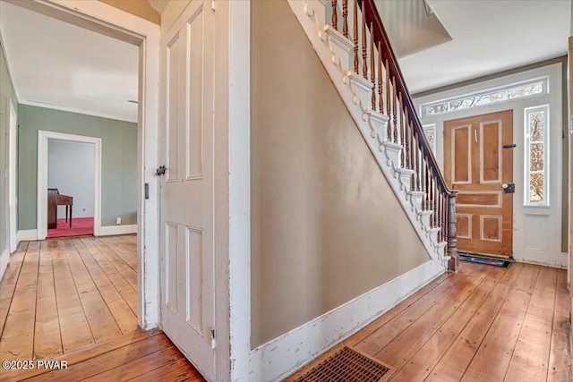 foyer entrance with baseboards, stairs, hardwood / wood-style floors, and crown molding