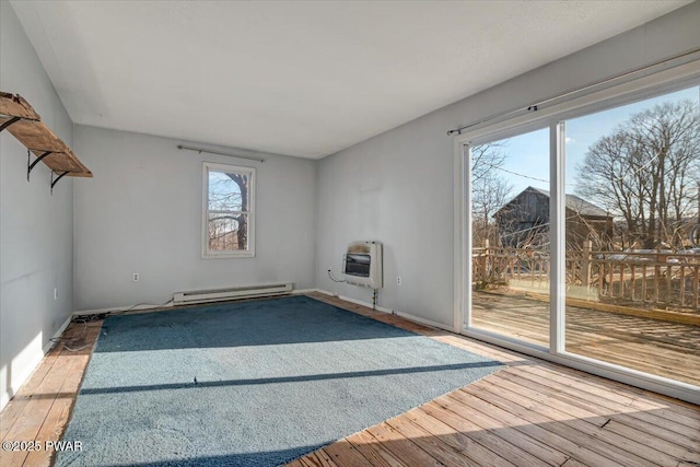 unfurnished living room with heating unit, wood finished floors, and baseboard heating