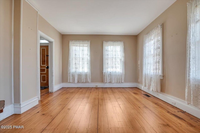 empty room featuring light wood finished floors and baseboards