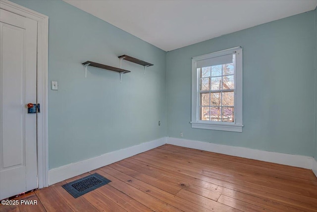 unfurnished room featuring baseboards, hardwood / wood-style floors, and visible vents