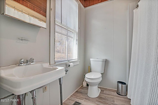 full bath with toilet, a shower with shower curtain, visible vents, and wood finished floors