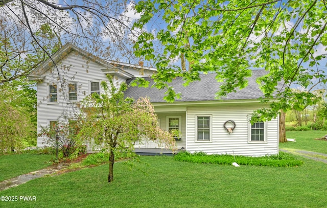 view of front facade featuring a front yard and a shingled roof
