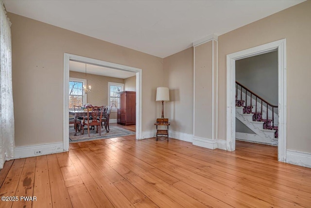 interior space with a chandelier, light wood-style flooring, baseboards, and stairs
