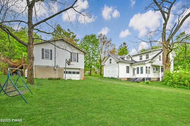 rear view of house featuring a lawn, a deck, and a garage