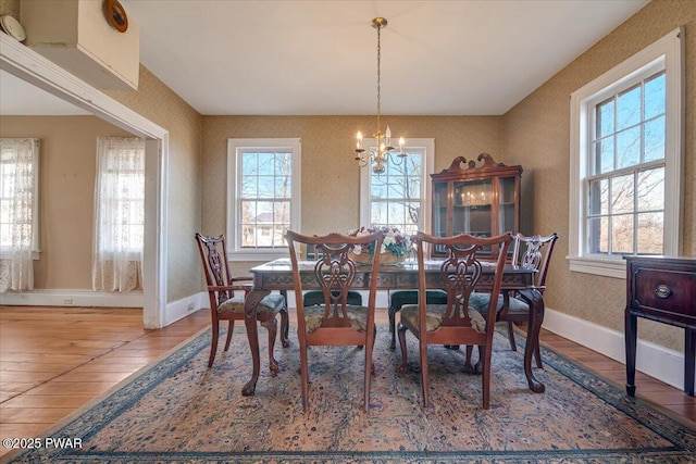 dining space featuring a chandelier, wood finished floors, and baseboards