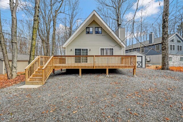 rear view of house with a wooden deck and a storage shed