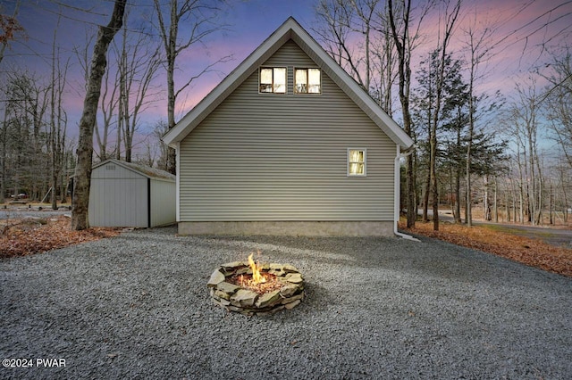 property exterior at dusk with a shed and a fire pit