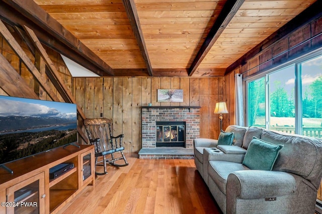 living room with wooden ceiling, a brick fireplace, beamed ceiling, wood walls, and hardwood / wood-style floors