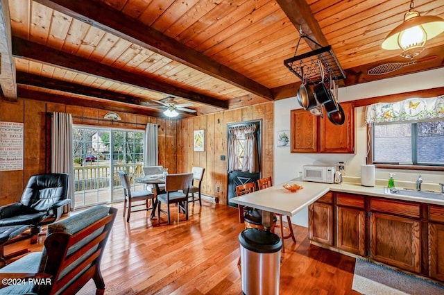 kitchen with pendant lighting, wooden ceiling, sink, wooden walls, and beam ceiling