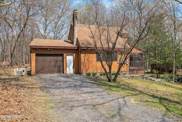 view of property exterior featuring a shingled roof, an attached garage, a chimney, and driveway