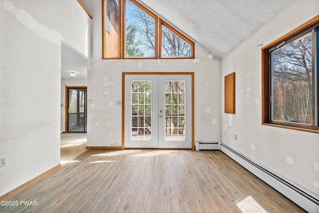 interior space featuring french doors, wood finished floors, baseboard heating, and high vaulted ceiling