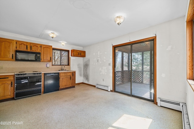 kitchen with a sink, baseboard heating, light countertops, brown cabinetry, and black appliances