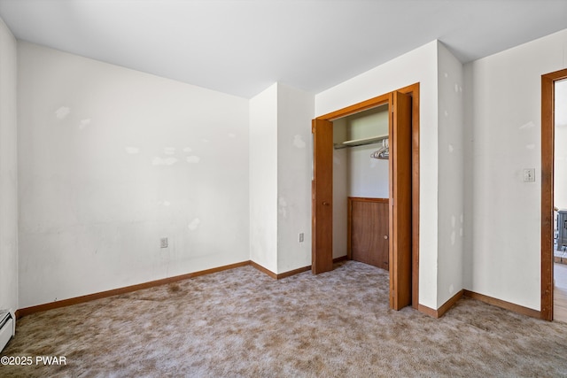unfurnished bedroom with baseboards, carpet flooring, a baseboard heating unit, and a closet