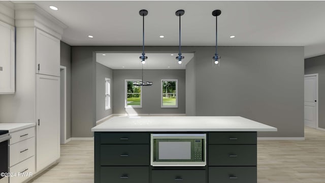 kitchen with built in microwave, white cabinets, light wood-type flooring, and a kitchen island