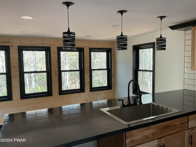 kitchen with wooden walls, sink, and pendant lighting